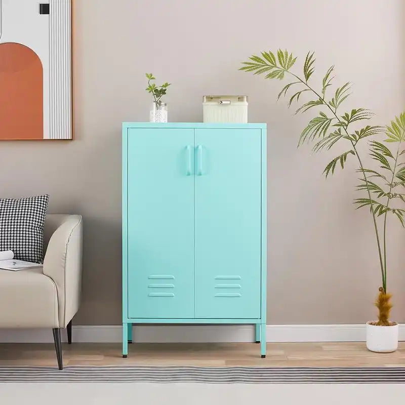 A closed mint green metal accent cabinet with tall legs standing neatly in a modern living room next to a sofa and plant.